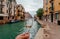 Venice with water canals and white wine glass in hand of happy traveler, Italy. Ancient italian city