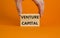 Venture capital symbol. Wooden blocks with words Venture capital on beautiful orange background, copy space. Businessman hand.