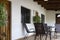 Veranda with chairs and table on the wooden floor. Front facade with door and windows and plants