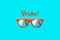 Verao text in Portuguese: Summer and orange sunglasses with palm tree reflections isolated in large cyan background