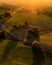 Vertical aerial of fields with a road in the middle flooded with sun rays at golden hour