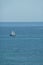 Vertical aerial shot of a sailboat in blue sea under clear sky