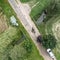 Vertical aerial view of the crossing of a stream under a narrow street with a power cable above it