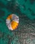 Vertical aerial view of a person parasailing over the turquoise sea