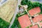 Vertical aerial view of a tennis court next to a house and a street with parked cars near a meadow in Germany