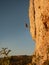 VERTICAL: Athletic female rock climber stops midway up a towering rocky cliff.