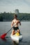 Vertical. Athletic handsome man in sunglasses and paddle on sup board on the river on the background of a beautiful landscape.