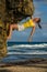 VERTICAL: Athletic woman lets go of the sharp rock while climbing up a boulder.
