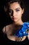 Vertical attractive seductive brunette woman with blue make up and orchid flower twig decoration on neck in black studio