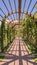 Vertical Beautiful garden wedding venue with a wooden arbor wrapped with vibrant vines