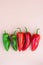 Vertical beige background with ripe mature organic red green bell peppers, harvest of different colores peppers in a row freshly c