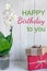 Vertical birthday card with orchid and box with a gift. Designer Birthday Greeting Card. Photo for blog, e-mail