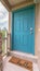 Vertical Blue green door of a home with doormat railing and stone pillar at the entrance