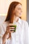 Vertical blurred portrait of cheerful attractive young woman holding glass with green vegetable detox smoothie cocktail