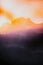 Vertical of a blurry skyline of mountains with dense forests under the sunset glow
