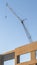 Vertical Building under construction with metal crane and blue sky background