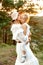 Vertical calm, loving woman, mother in hat holding little blonde daughter in dress in arms, embracing. Foster family