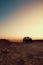 Vertical of a car in a dusty rural area at sunset.