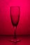 Vertical close up beautiful photo of empty shiny champagne glass standing on table. An empty transparent glass isolated on pink ba