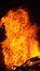 VERTICAL, CLOSE UP: Blazing hot fiery flames engulfing a big pile of firewood.