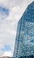 Vertical close-up on a building with mirrored windows which reflects a blue sky with clouds. Business and construction