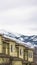Vertical Close up of facade of townhomes with snowy mountain and cloudy sky background