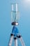 A vertical close - up image of a medicine ampoule turned upside down and five medical needles stuck in the bottle cap on a blue