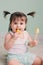 Vertical close up indoor portrait of cute baby girl playing with easter decorations