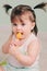 Vertical close up indoor portrait of cute baby girl playing with easter decorations