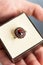 Vertical close-up of man hand holding jewelry box with big engagement garnet ring. Large beautiful dark red garnet ring in box.