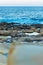 Vertical close-up picture of stone coastline with blue sea and sky in evening. Maltese coast in Sliema, Malta. Tranquille sea