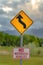 Vertical Close up view of a Winding Road Ahead sign and No Motorized Vehicles sign