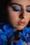 Vertical closeup cool, mysterious, romantic brunette female face with black eyebrows with blue make up and iris flowers