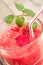 Vertical closeup of a glass of raspberry smoothie, with a plastic straw