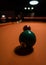 Vertical closeup of a green ball on an orange billiard board under the light