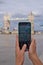 Vertical closeup of the hands of a person photographing the Tower bridge with a smartphone
