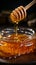 Vertical closeup honey flows from wooden stick to jar, highlighting natural purity