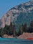 Vertical closeup of a lake, tree, rocky, forested mountain clear sky background