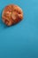 Vertical closeup shot of a baked honey bun on a blue background