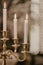 Vertical closeup shot of beautiful white burning candles on a golden holder