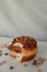 Vertical closeup shot of a bitten walnut donut with chocolate filling on a white plate with nuts