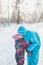 Vertical closeup shot of a cute little girl kissing a female in a fluffy blue costume