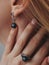 Vertical closeup shot of a female wearing a ring and earrings with a black pendant