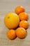 Vertical closeup shot of five tangerines around an orange on a wooden surface