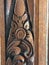 Vertical closeup shot of a flower-like pattern carving on a wooden door