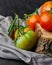 Vertical closeup shot of fresh green and red tomatoes on a tree stump on a black background