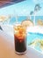 Vertical closeup shot of a glass of cold coke with lemon on a bar table near the beach