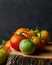 Vertical closeup shot of green and red tomatoes on a tree stump on a black background