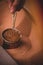 Vertical closeup shot of a hand brewing Turkish coffee in the sand