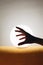 Vertical closeup shot of a hand silhouette in front of a moon-shaped lamp on a yellow tablecloth